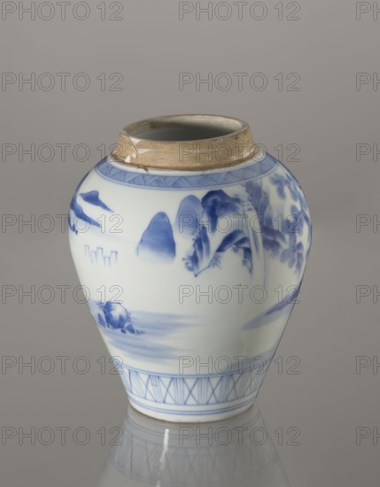 Storage vessel with lid by Zôshuntei Sanpo signed Zoshuntei Sampo zo, c. 1842–1878, Arita, Japan. Blue-and-white porcelain, pear-shaped body with flat cylindrical lid; height 21.8 cm, diameter 15.3 cm. Decorated in cobalt in several tones with a Chinese-style landscape: an old man resting under a pine on a rocky cliff overlooking a wide body of water, with waterfall, lofty peaks, and boat sails on the horizon. Lower base features a wide ornamental band of three vertical and two crossed lines; neck and lower edge of lid have diagonal-line bands forming triangular motifs; lid painted with a rock motif. Decoration modeled on Chinese Southern School painting and the Japanese bunjinga nanga movement; free-form painting and precise, masterful lines indicate an excellent porcelain decorator. Materials and technique: blue-and-white porcelain, underglaze cobalt. Cultural context: Edo–Meiji period Edo 1603–1868; Meiji 1868–1912., An off-white ceramic jar with a rounded body and a narrow open nec...