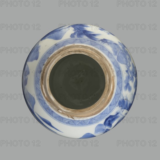 Storage vessel with lid by Zôshuntei Sanpô signed Zoshuntei Sampo zo, c. 1842–1878, Arita, Japan. Pear-shaped blue-and-white porcelain storage pot with flat cylindrical lid. Decorated in cobalt in several tones with a Chinese-style landscape: an old man resting under a pine on a rocky cliff overlooking a broad body of water, with mountainous scenery, a waterfall, lofty peaks, and distant sails. Lower base has a wide ornamental band of three vertical and two crossed lines; neck and lower edge of lid have diagonal-line bands forming triangular motifs; lid decorated with a rock motif. Decoration modeled on Southern School Chinese painting that influenced Japanese bunjinga/nanga; free-form painting with precise, masterful lines indicating a highly skilled decorator. Height 21.8 cm; diameter 15.3 cm., A top-down view of a round ceramic vessel with a wide opening, showing a glossy interior that appears dark gray, a rim with exposed unglazed beige clay, and an exterior decorated with blue bru...