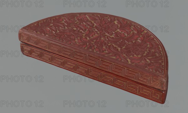 Box with a lid, ; Chinese art; Chinese; Ming 1368–1644; semi-circular box decorated on the lid with a dense pattern composed of peony flowers and leaves; rim decorated with a Chinese meander motif; motifs include peonies, leiwen meander ornament, and lemons; 17th century; China; container; height 4.4 cm, width 24.0 cm, depth 10.7 cm., A semicircular carved object with a floral relief pattern on its top surface and a geometric border along its curved edge, rendered in shades of red with highlights of gold and darker red accents, set against a pale grey background.