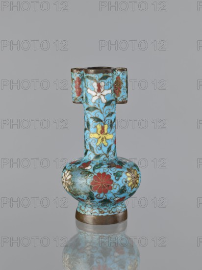 Vase, cloisonné enamel, gilding, Chinese, Qing 1644–1911, 19th century, China; plant ornament/decoration; vessel; height 13.0 cm, diameter 6.8 cm;, A small ornamental vase with a bulbous base, a narrow neck, and a rectangular-shouldered rim, decorated all over in a bright turquoise blue background with floral motifs in red, white, yellow, green, and gold, and with visible metallic rims at the top and base; the surface shows curling vine patterns and stylized flowers, and the object sits on a reflective surface producing a soft mirrored reflection against a plain gray backdrop.