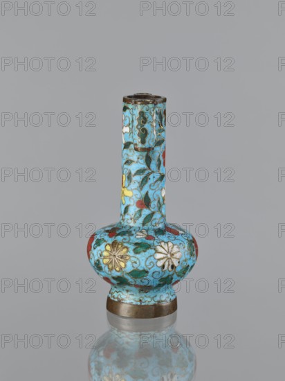 Vase, cloisonné enamel, gilding, Chinese, Qing dynasty 1644–1911, 19th century, China; plant ornament/decoration; vessel; height 13.0 cm, diameter 6.8 cm., A small ornamental vase with a long narrow neck and a rounded bulbous body sits against a plain gray background, covered in a bright turquoise glaze decorated with a floral cloisonné pattern in colors including yellow, white, red, green, and dark blue, with fine dark outlines and small scrolling vine motifs; the rim and base have metallic bands in a bronze tone, and the vase is reflected faintly on the glossy surface beneath it.