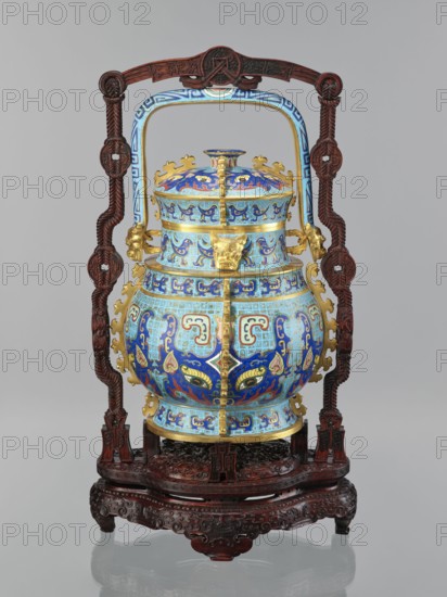 You-type vessel with a lid on a stand;, Chinese, Qing dynasty, Qianlong period 1736–1795. Cloisonné cellular enamel ritual/ceremonial you vessel with elaborate, precise, multi-colored decoration on body and lid depicting a taotie mask and stylized bird images, motifs borrowed from archaic bronzes. Plastic insets on the sides and animal head terminals on the movable handle. Originally used as a vessel for storing alcoholic beverages you, Shang dynasty function. Wooden stand of elongated shape, mattly polished rosewood, decorated with bas-relief symbolic representations bats and spiral ornament. Dimensions: vessel H 39.0 cm, W 24.0 cm, D 19.0 cm; weight 5.6 kg. Stand: H 55.0 cm, W 30.0 cm, D 18.0 cm; weight 1.8 kg., An ornate vessel with a domed lid sits in a carved wooden stand; the vessel is predominantly blue with lighter blue and turquoise sections and gold accents, and it features intricate swirling and geometric enamel patterns in darker blue, red, and touches of green and yellow. ...