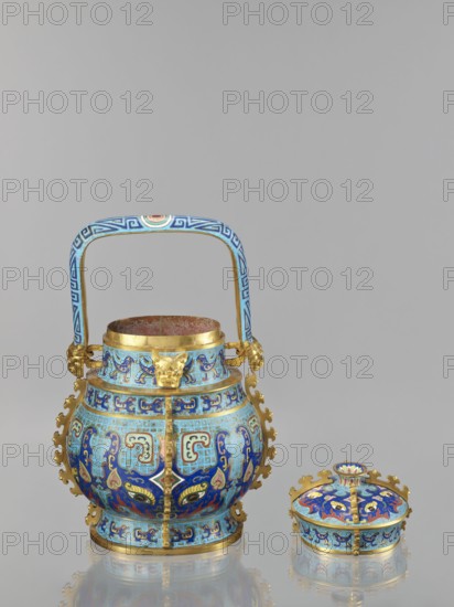 You-type vessel with a lid on a stand, Chinese, Qing dynasty, Qianlong period 1736–1795. Cloisonné cellular enamel ritual/ceremonial you vessel with elaborate, precise, multi-colored decoration depicting a taotie mask and stylized bird images, motifs borrowed from archaic bronzes. Plastic insets decorate the sides and animal head terminals flank the movable handle. Wooden elongated stand, mattly polished rosewood, decorated with bas-relief bats and spiral ornament. The you form with lid and movable handle was originally used to store alcoholic beverages during the Shang Dynasty. Materials: cloisonné enamel, metal, wood. Dimensions: vessel H 39.0 cm, W 24.0 cm, D 19.0 cm, weight 5.6 kg; stand H 55.0 cm, W 30.0 cm, D 18.0 cm, weight 1.8 kg., A decorative metal vessel with a handle and a separate lid sitting on a reflective surface; the vessel has a bulbous body with ornate attached fittings and a curved rectangular handle rising above it, all decorated with intricate patterns and designs...