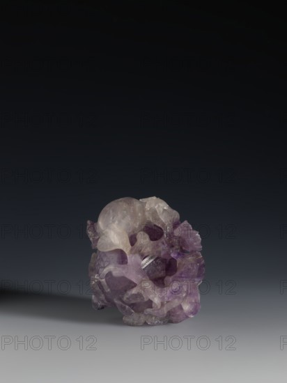 Pomegranate-shaped vessel, Chinese, Qing dynasty 1644–1911, decorated with pomegranates and frogs, 18th–19th century, China; vessel; height 10.2 cm, width 9.6 cm, diameter 7.2 cm., A translucent sculpted object with irregular organic shapes and smooth rounded forms sits on a smooth surface against a dark gradient background, displaying a mix of purple, pale lavender, clear, and subtle gray tones with light reflections on its glossy surfaces.