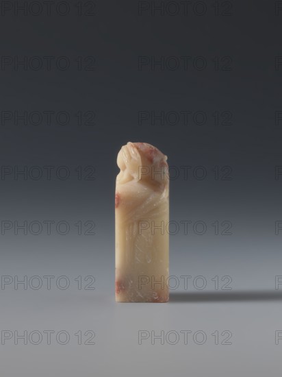 Seal stamp, hares, Chinese art, seal stamp, Chinese, Qing 1644–1911, late 19th century, China; sculpture; height 5.7 cm, width 1.8 cm, thickness 1.7 cm, A small vertically oriented carved object stands alone on a smooth surface against a gradient background; the object is mainly cream-colored with areas of reddish-brown mottling, and its top is carved into a rounded, figurative shape while the lower portion is rectangular and smooth with subtle carved lines and scratches.