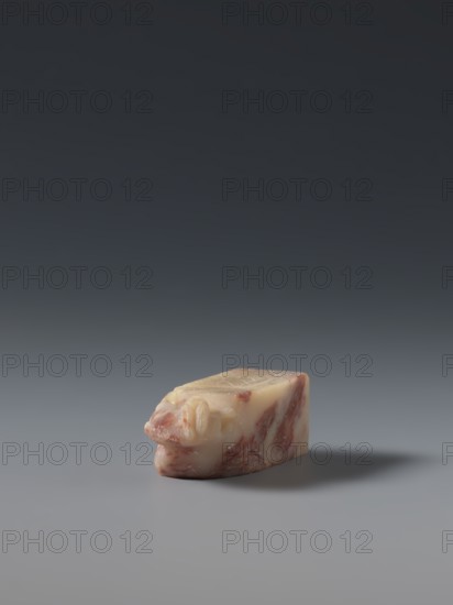 Seal stamp, maker, ; subject: hares; Chinese; medium: seal stamp sculpture; culture: Qing dynasty 1644–1911, late 19th century; origin: China; dimensions: height 5.7 cm, width 1.8 cm, thickness 1.7 cm., A small, irregularly shaped object sits on a smooth surface with a soft shadow extending to one side; the object shows a marbled pattern of pale cream and pinkish-red tones with a glossy, slightly translucent appearance and rounded, organic contours, while the background transitions from a lighter gray near the surface to a darker gray toward the top of the image.