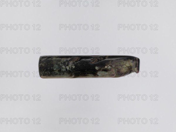 Pig — funerary figurine; maker, Chinese; Han dynasty 202 BCE–220 CE; jade; animal subject pig; zodiac sign; full sculpture; funerary figurine; 2nd century BCE–3rd century CE; sculpture/figurine; dimensions: height 2.2 cm, width 9.5 cm, depth 2.4 cm; weight 0.12 kg., A horizontally oriented cylindrical object floats against a pale gray background, showing a mottled surface with dark green, black, muted brown, and hints of pale blue and purple; the object has a glossy, worn texture with irregular patches and small areas of lighter discoloration, rounded ends with one end slightly indented, and subtle unevenness along its length.