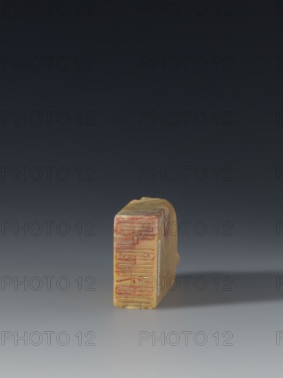 Seal stamp, Chinese, Qing dynasty 1644–1911, Qing style; seal stamp depicting sages and officials; 18th–19th century, China; sculpture; height 8.2 cm, width 3.3 cm, depth 1.6 cm, A small rectangular object rests upright on a smooth surface with a soft shadow extending to the right; the object has a marbled appearance with yellow and beige tones and visible streaks of red and pink on its front face and along the top, and there are subtle areas of brown and off-white within the material, while the background transitions from a dark gray at the top to a lighter gray near the surface.