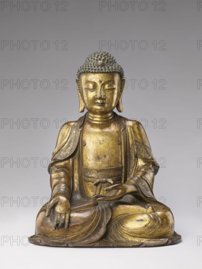 Shakyamuni Buddha, Chinese, Qing dynasty 1644–1911, 17th–18th century. Sculpture bronze or unspecified, height 47.0 cm, width 26.0 cm. Iconography: Chinese Buddhism; Buddha, ushnisha; tutelary deities., A seated statue of a figure with closed eyes and a calm facial expression, rendered in a metallic golden color with darker patina and traces of greenish tones on the hair, sitting cross-legged on a rounded base; the figure wears flowing robes with decorative patterns visible in the folds and edges, the hands resting in a gesture with one hand open and the other palm up, and the head topped with textured, rounded curls.