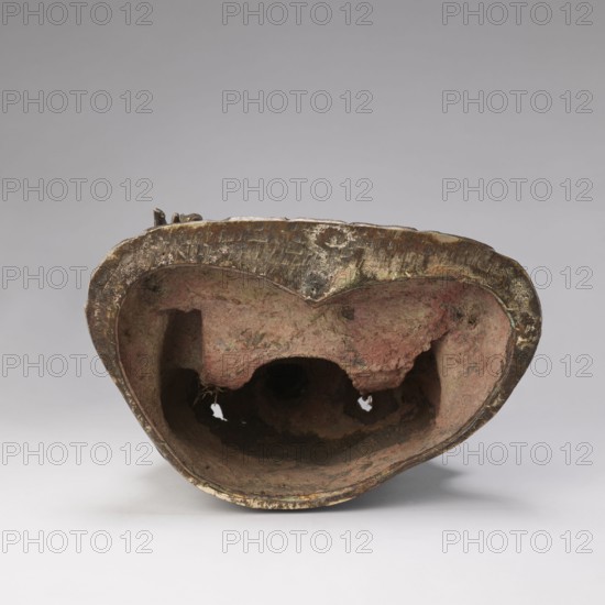 Shakyamuni Buddha, unknown provenance; Chinese art, Chinese culture; Qing dynasty 1644–1911, Qing style; Chinese Buddhism; tutelary deities iconography, Buddha iconography, ushnisha; 17th–18th century, China; sculpture; height 47.0 cm, width 26.0 cm, An irregular hollow object with a rough textured interior and exterior, showing a worn metallic rim with a patina in shades of brown and dull gold, and an interior surface in muted reddish and pinkish tones with areas of darker brown and black; the hollow has uneven edges and several openings, and the piece rests on a smooth light gray surface against a pale gray background.