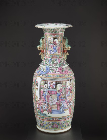 Vase, Chinese, Qing dynasty 1644–1911, colored porcelain ceramics, decorated with lizards and a lion, figurative and genre scenes, plant motifs with fruit in the background; vessel, 2nd half of the 19th century, height 90 cm, diameter 37.5 cm., A tall porcelain vase sits against a dark background, predominantly showing colors of pink, green, blue, white, gold, and red; the vase has a flared rim with floral motifs and a narrow neck that expands to a rounded body, decorated with painted panels depicting groups of people in traditional dress inside architectural settings, surrounded by scrolling floral and foliate patterns; there are sculpted handles on each side shaped like stylized creatures finished in green and gold with red accents, and additional applied ribbon-like ornament in blue and pink on the shoulder; the lower body features a geometric band with floral medallions and a base rim with a thin colored line.