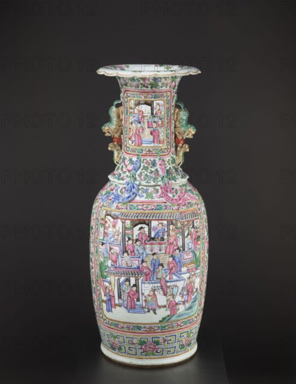 Vase, manor property Ruchna, Chinese art, Chinese culture, Qing 1644–1911, colored porcelain, ceramics; motifs: lizards, lion, figurative scenes, genre scenes, plant motifs with fruit in the background; style: Qing; type: vessel/ decorative vase; 2nd half of the 19th century; China; height 90 cm, diameter 37.5 cm, A tall, ornate porcelain vase stands against a dark background, featuring a flared rim and a long neck with decorative handles shaped like stylized animal heads. The vase surface is covered in detailed painted scenes showing groups of people in interior and exterior settings, with architectural elements and decorative borders. The overall color palette includes pink, green, blue, gold, white, and touches of red and purple. Floral motifs and scrolling patterns appear around the neck and shoulder, and ribbon-like raised decorations in pink and blue wrap the upper body. The lower section displays a geometric band with floral accents above a white base.