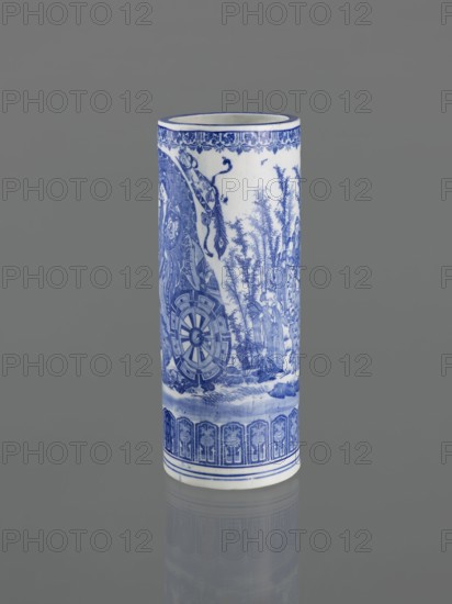 Vessel by, Narozno Eckersdorf, Japanese, 19th century, ceramics; decorative figurative vessel depicting female images; height 39.3 cm, diameter 15.5 cm; Japanese art; restitution provenance., A cylindrical porcelain vase stands upright against a plain gray background, decorated with detailed blue painted scenes and patterns on a white surface; the top rim has a thin blue band and a floral border in blue, the main body shows a complex blue landscape with tall bamboo-like plants, human figures, and a cartwheel motif, and the lower section features a repeating architectural-style blue border above thin blue rings near the base; colors visible include blue, white, and gray.