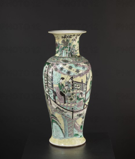 Vase, park scenes with architecture, enamel paints, Chinese art, Chinese culture, ceramics, decorative vessel, colored porcelain, 19th century, China, vessel, height 59.5 cm, diameter 25.5 cm, A tall porcelain vase with a flared rim and rounded shoulder standing on a short foot, decorated all over with painted scenes and patterns in pale yellow, mint green, soft pink, black, and white, with touches of darker green; the neck shows a garden scene with stylized trees and plants and a patterned band at the shoulder, the main body depicts a group of figures seated and standing on a tiled floor beneath draped cloths and decorative medallions, framed by architectural elements including railings and patterned panels, while the lower section features an arched bridge and water motif with brickwork and foliage; the overall surface combines delicate line work, floral motifs, and geometric borders, set against a dark neutral background.