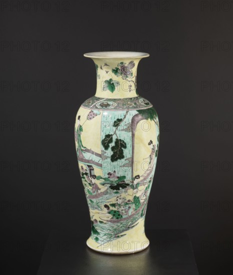 Vase, creator unknown, park scenes with architecture, enamel paints, Chinese art, Chinese culture, ceramics, decorative vessel, colored porcelain, provenance unknown, 19th century, China, vessel, height 59.5 cm, diameter 25.5 cm, A tall ceramic vase with a flared rim stands against a dark gray background; the vase has a pale yellow base color with painted scenes in green, turquoise, purple, and black. The neck shows botanical motifs with green leaves and purple flowers, and the shoulder has a decorative band with intricate green and purple patterns. The body features a vertical panel of turquoise with dark green foliage and surrounding narrative scenes depicting several figures wearing robes in green and purple tones, some seated and some standing, set among stylized rocks, water, and plants in green and turquoise. The lower portion includes aquatic plants and leaves in various greens, with accents of purple and black linework throughout, and the vase sits on a pale yellow foot with a ...