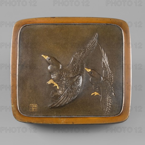 Box with a lid, Jômi, Eisuke I 1839-1899 artist; geese, grass; rectangular box with rounded corners, decorated on the flat lid with two flying wild geese in high relief with inlay of silver and gold iro-e zogan technique; side walls decorated with a motif of inclined reeds in silver and shakudo using the hira-zogan technique, giving a painted effect; lid bears a gold signature in a square field with two stylized kanji characters resembling archaic ones: Shobi; ca. 1880–1899 Meiji Period, 1868–1912, Kyoto, Japan; container; height 4.8 cm, width 10.2 cm, depth 11.4 cm, A square metal plaque with rounded corners sits against a neutral gray background; the plaque has a warm brown and bronze outer rim and a darker brown central field that shows a raised relief of two birds in flight. The birds are rendered in darker brown metal with polished feather texture, and they have contrasting gold-colored beaks and feet. The larger bird is positioned on the left with wings spread upward and tail fea...