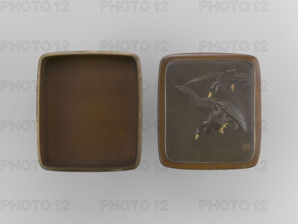 Box with a lid, Jômi, Eisuke I 1839–1899 artist; . Rectangular box with rounded corners, decorated on the flat lid with two flying wild geese made in high relief with inlay of silver and gold iro-e zogan technique. The side walls are decorated with a motif of inclined reeds, made of silver and shakudo using the hira-zogan technique, where the decorative motif is level with the background surface producing a painted effect. On the lid there is a signature in gold in a square field of two stylized kanji characters resembling archaic forms: Shobi. Ca. 1880–1899 Meiji Period, 1868–1912, Kyoto, Japan. Container. Height 4.8 cm; width 10.2 cm; depth 11.4 cm., A pair of rectangular trays displayed side by side on a light gray background, one tray shown open with a smooth brown interior and slightly worn outer rim with hints of beige, the other tray closed with a darker brown surface featuring a raised design of a group of birds in flight with detailed feathers and golden beaks and feet, the cl...