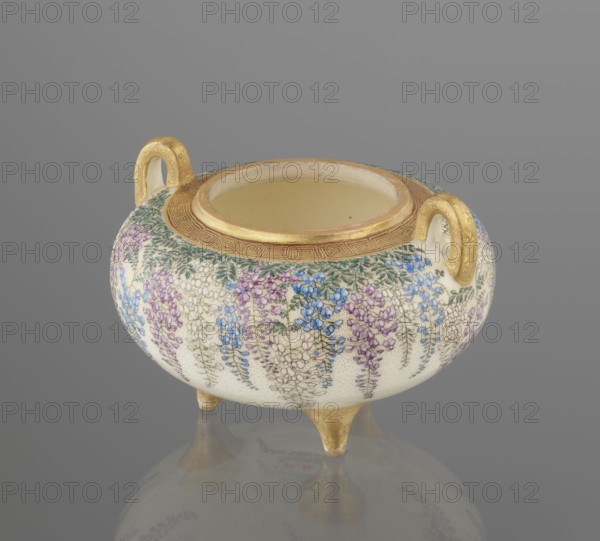 Incense burner koro with cover by Kinkozan Sobei VII 1867–1927, Kinkozan workshop; decorated in Kyoto Akata/Awata style, Meiji period 19th/20th century. Ceramic satsuma censer okimono with wisteria and chrysanthemum floral decoration; tripod form with two handles. Signed. Height 7.8 cm; diameter 9.5 cm., A round ceramic vessel with a wide open top stands on three short pointed feet and has two small loop handles; the surface is decorated with hanging floral motifs in shades of purple, blue, and green on a cream background, and the rim, feet, and handles are highlighted in gold with a patterned gold band around the mouth; the background is gray.