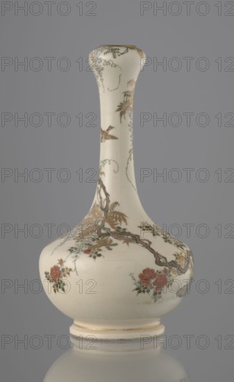Vase, Yabu Meizan 1853–1934, c. 1900 Meiji 33, Japan, Osaka. Onion-shaped vase on a low ring foot with a long, slender neck bulging at the spout. Decorated with a freely composed kachôga flowers-and-birds motif: a golden-leafed wisteria vine with white blooms entwines the neck, growing from the rock on which a sparrow perches; a tall rose bush with white and red blooms grows beside the wisteria; two sparrows, painted in gold and iron black, fly around the plants. A small, delicately hatched black-and-gold ornament is placed in the lower part of the belly. Warm milky glaze with very fine cracklework; thin gold stripe around the foot and gilded rim. Gold-painted brand on the bottom in a square cartouche with three kanji characters: Yabu Meizan. Ceramic satsuma; height 15.0 cm, diameter 8.0 cm., An off-white ceramic vase with a long narrow neck and a rounded body sits against a plain gray background; the vase is decorated with painted floral and branch motifs in muted colors including gol...