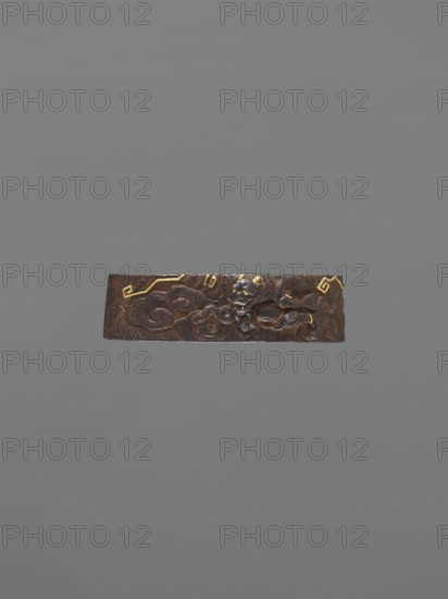 Metal collar ending a sword hilt fuchi, Oni demons motif, Japanese, Edo period 1603–1868, 18th century, katana hilt fitting, materials: metal, dimensions: height 3.9 cm, width 2.3 cm, depth 1.1 cm., A horizontal brown metal band with a textured, carved surface sits against a plain gray background; the band shows a raised, sculpted design including a small carved face or mask and swirling cloud-like forms, and there are a few small gold accents on the band.