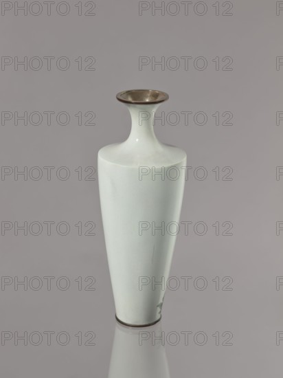 Vase, gift; symmetrical decoration: blooming poppies on a grey-blue background; cloisonné enamel; flowers poppies; Meiji–Taisho period, ca. 1910–1920; Nagoya, Japan; vessel; height 24.5 cm, diameter 9.0 cm., A tall, narrow vase with a flared neck and rounded mouth stands against a plain background; the vase is mostly pale blue-green with a smooth, glossy surface, a metallic dark rim at the mouth and base, and a small area of darker green near the bottom, all reflected faintly on the surface beneath it.