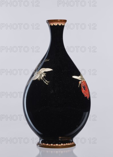 Vase, gift, Meiji 1868–1912, Japanese, cloisonné enamel, vase decorative vessel depicting birds/cranes, 19th/20th century Meiji Period, Nagoya, Japan; height 18.3 cm, diameter 10 cm., A glossy black vase with a teardrop shape and a narrow neck stands against a pale gray background, showing shiny reflections on its surface and tiny speckled highlights; a decorative band in brown and cream encircles the rim and base, and there are painted motifs of white and gold birds with detailed feathers and a bright red flower on the curved body.