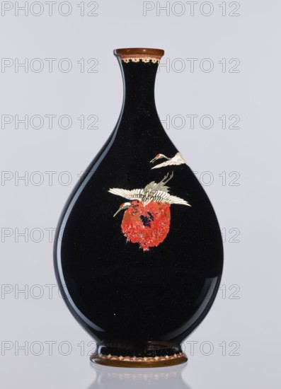 Vase, Meiji period 1868–1912, Nagoya, Japan; cloisonné enamel; decorative vessel/vase depicting cranes birds; 19th–20th century; height 18.3 cm, diameter 10 cm., A glossy black teardrop-shaped vase with a narrow neck and flared rim, featuring a decorative band of brown and cream at the rim and base, shows a painted scene of white birds with red accents around their heads interacting with a textured red element on the body; the vase reflects light on its curved surface and sits against a pale gray background.