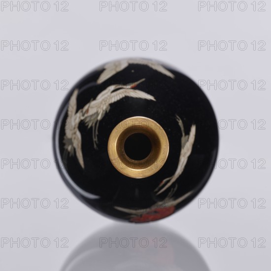 Vase, Meiji period 1868–1912, Nagoya, Japan; cloisonné enamel; decorative vessel vase depicting birds—cranes; height 18.3 cm, diameter 10 cm; 19th/20th century., A round object with a black surface and a central circular opening rimmed in metallic gold, decorated with a few white bird-like shapes and small areas of red, shown against a light gray background with a faint reflection below.