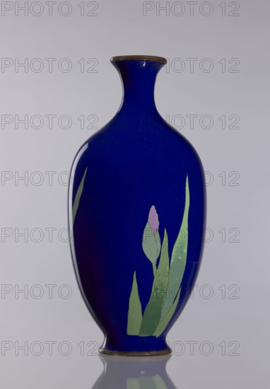 Vase, ; cloisonné enamel; irises; Japanese art; Japanese; flowers iconography; vases, flower vase, decorative vessel; Meiji 1868–1912, late 19th century; Japan; vessel; height 17.7 cm, diameter 8.4 cm., A deep blue vase with a narrow flared neck and rounded body stands upright against a pale gray background, showing a smooth glossy surface and a subtle reflection beneath it; a stylized floral motif appears on one side with green elongated leaves and a single small pale pink bud, and the rim and base show a thin brownish edge.