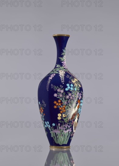 Vase, cloisonné enamel, wisteria, hens, flowers, roosters iconography, Japanese art, vases, decorative vessel, Meiji 1868–1912, Ovoid vase, elongated with a long thin neck slightly flared at the spout, navy blue background of the decoration, c. 1890–1910, Japan, vessel, height 15.6 cm, dia. 5.6 cm, width 6.4 cm, A tall, slender vase with a deep navy background and a narrow neck flaring slightly at the rim, decorated with a rich painted design of floral sprays and foliage in colors including pale purple, light blue, turquoise, green, orange, yellow, white, and brown, with metallic gold accents on the rim and base; the painted scene features clusters of small flowers, drooping wisteria-like blossoms, leafy stems, and a stylized bird with long feathers, all reflected faintly on the smooth surface beneath the vase.
