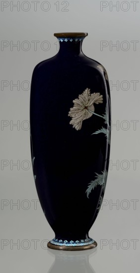 Vase, Meiji period ca. 1900, Nagoya, Japan. Cloisonné enamel angular vase one of a pair with rounded edges, low round foot and short neck slightly flaring at the spout. Bottom of the foot and edge of the spout are framed in silver-plated copper. Against a uniform dark garnet surface with a purple hue, a tall flower grows from the base to the neck: stems with alternating elongated jagged leaves in pale grayish green support large full corollas of white and light purple flowers with dense yellow stamens and a green pistil. Motif executed in yusen technique, with thin silver wires structuring leaves and petals; stems accentuated with chocolate brown enamel. Flowers differ slightly between the pair to enhance naturalness. Around the foot and neck is a border of small geometric semicircle and rhombus motifs in white and two shades of blue, also in yusen technique. Vessel; height 18.4 cm, width 7.5 cm, depth 7 cm., A tall, slender vase with a rounded shoulder and narrow neck in deep navy blu...