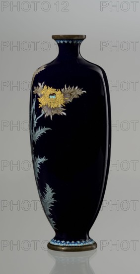 Angular vase one of a pair with rounded edges, on a low round foot and with a short neck slightly flaring at the spout. The bottom of the foot and the edge of the spout are framed in silver-plated copper. Against a uniform dark garnet background with a purple hue, a decoratively but faithfully depicted tall poppy grows from the base to the neck. Stems with alternating, elongated, jagged leaves in pale grayish green support large, full corollas of white and light purple flowers with dense yellow stamens and a green pistil; the motif is executed using the yusen technique, with thin silver wires precisely structuring the delicate, jagged forms of the leaves and petals. The plant stems are accentuated with chocolate brown enamel. The flowers are presented slightly differently in each vase of the pair, enhancing the impression of naturalness. Around the foot and the edge of the neck is a border of small geometric semicircle and rhombus motifs in white and two shades of blue, also made in th...