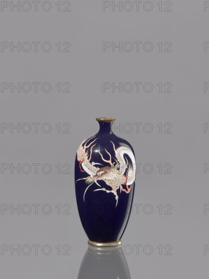 Vase;, Japanese Meiji period 1868–1912, late 19th–early 20th century. Cloisonné enamel on metal vessel, decorated with Japanese dragon motif. Height 9.5 cm; diameter 4.6 cm., A small vase with a deep navy blue glossy surface sits against a plain gray background; the vase has a narrow neck with a slightly flared rim in a muted gold tone and a matching base, and a decorative depiction of a coiled dragon wrapping around the body rendered in white, cream, pale brown, and touches of red and pink with thin flowing accents in a light yellowish-gold.
