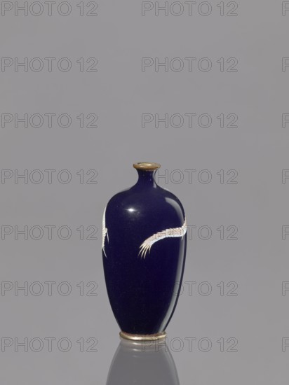Vase, dragons iconography, Japanese art, Japanese culture, Japanese dragon motif, Meiji 1868–1912, cloisonné enamel, 19th/20th century Meiji Period, Japan, vessel; height 9.5 cm, diameter 4.6 cm, A small, glossy vase with a deep navy blue surface and a narrow neck topped with a thin metallic rim, decorated with a pale, feathery motif wrapping around its midsection, standing on a metallic base and reflected faintly on the gray background; visible colors include navy blue, pale cream, metallic gold, and gray.