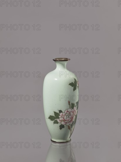 Vase, gift, repossession, Japanese, peonies, Meiji 1868–1912, cloisonné enamel, flowers iconography, symmetrical decoration, ca. 1900–1910 Meiji Period, Japan, vessel; height 12.3 cm, diameter 5.3 cm, A pale green ceramic vase with a narrow neck and flared rim sits upright on a reflective surface, showing a painted floral design featuring pink blossoms and dark green leaves on one side; the rim and base have a darker, metallic-looking band, and the background is a smooth muted gray.