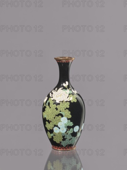 Vase, cloisonné enamel; symmetrical decoration; chrysanthemums and flowers iconography; Meiji period, ca. 1900 1868–1912; Nagoya, Japan; vessel; height 19.3 cm, diameter 9.1 cm., A tall, narrow-necked vase with a glossy black surface decorated with floral motifs, showing a group of pale cream and light blue flowers with green leaves, a rim with a band of reddish-brown and metallic gold, and a similar reddish-brown decorative band at the base, all set against a plain muted gray background.
