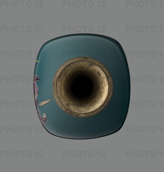 Vase, ovoid one of a pair, slender, on a low ring-shaped foot and a narrow neck flaring at the rim; foot and mouth framed with sheet metal. Decorated with a motif of a blooming iris bush, rendered naturalistically with a variety of color tones, executed using the yusen cloisonné enamel technique against a uniform sea-green background. Narrow, colorful borders around the foot and rim, also in yusen, composed of small triangular forms called cicada wings. Japanese, Meiji period ca. 1900, Nagoya. Vessel; height 25 cm, width 9.7 cm, depth 8.8 cm., A top-down view of a rounded square vase with a central circular opening showing an aged metallic interior and a deep dark void, the exterior surface in teal with small visible speckles and a few decorative floral motifs in purple and pale yellow along one side, set against a uniform gray background.