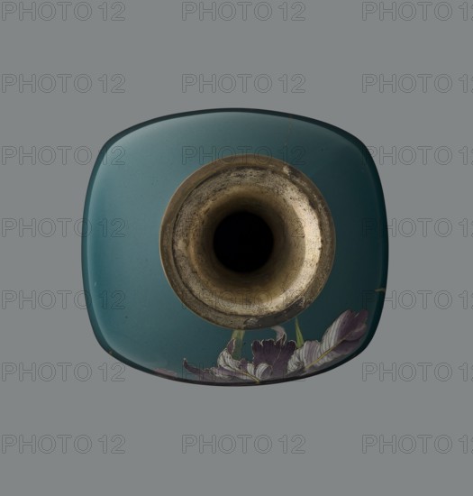 Vase, ovoid one of a pair, slender, on a low ring-shaped foot with a narrow neck flaring at the rim; foot and mouth framed with sheet metal. Decorated with a motif of a blooming iris bush rendered naturalistically with varied color tones, executed using the yusen cloisonné enamel technique against a uniform sea-green background. Narrow colorful borders of small triangular cicada wing forms around the foot and rim. Ca. 1900 Meiji period, 1868–1912, Nagoya, Japan. Vessel. Height 25 cm; width 9.7 cm; depth 8.8 cm., A top-down view of a square-shaped teal ceramic object with rounded corners and a central circular opening rimmed in aged metallic gold; the interior of the opening is dark and worn with textured brown and gray tones. Along the lower edge of the ceramic surface is a group of painted flower petals in shades of purple, lavender, white, and hints of green. The background is a uniform medium gray.