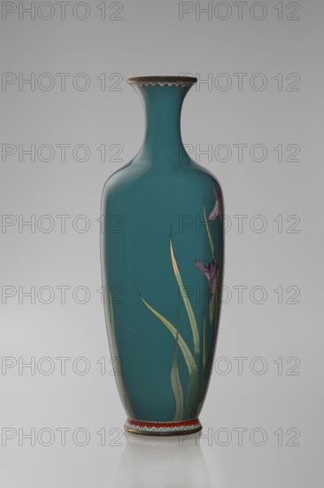 Vase, ovoid vase one of a pair, slender, on a low ring-shaped foot with a narrow neck flaring at the rim. Foot and mouth framed with sheet metal. Decorated with a motif of a blooming iris bush rendered naturalistically with varied color tones. Executed using the yusen cloisonné enamel technique against a uniform sea-green background. Narrow colorful borders of small triangular cicada wing forms around the foot and rim. Meiji period, ca. 1900. Japan, Nagoya. Vessel; height 25 cm, width 9.7 cm, depth 8.8 cm., A tall, slender ceramic vase with a narrow neck and flared rim in a deep teal color, decorated with painted long, slender green leaves and a few purple flower petals on one side, a thin band with a repeating scalloped pattern in red, white, blue, and gold around the base and a matching narrow decorative band beneath the rim, and subtle highlights and reflections on the glossy surface against a soft gray background.