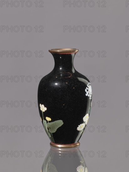 Vase, chrysanthemums; butterflies; Japanese art; Japanese culture; flowers iconography; Meiji 1868–1912; cloisonné enamel; Vase with a short, flared neck; ca. 1890–1910 Meiji Period; Japan, Nagoya; vessel; height 12.1 cm; diameter 6.8 cm, A glossy black vase with a narrow neck and flared rim is shown against a neutral gray background, decorated with painted floral motifs including white blossoms with yellow centers and green leaves, pale yellow buds, and small white clustered flowers; the rim and base have metallic bronze-colored accents and a thin band of red, and the vase's surface shows subtle speckling and reflections with a mirrored reflection of the vase visible on the surface below.