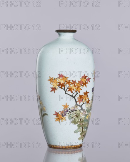 Vase, cloisonné enamel; chrysanthemums and maples plant ornament; decorative ovoid vase, elongated with a narrow spout; Japanese art, Meiji 1868–1912/Taisho 1912–1926, ca. 1910–1920; Japan, Nagoya; flowers iconography; vessel; height 12.4 cm, diameter 16.3 cm., A pale blue ceramic vase with a narrow neck and small dark rim stands against a soft gray-lavender background, decorated with a painted scene of a tree branch bearing orange, yellow, and reddish leaves and clusters of small flowers in shades of white, purple, and yellow, with green foliage beneath; a decorative band in brown and orange runs along the base, and the vase's glossy surface creates a faint reflective sheen at its bottom.