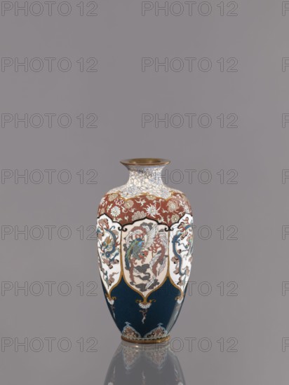 Vase, cloisonné enamel. Vase on a small, ring-shaped foot with a short neck ending in a spout widening toward the top. Decoration: stylized plant ornament in six reserves alternating dragon and phoenix motifs Japanese dragon, hoo/phoenix. Meiji period, ca. 1890–1900. Japan, Kyoto. Vessel; height 15.0 cm, diameter 8.0 cm., A decorative vase with a flared rim and rounded body sits centered against a plain gray background, displaying a color palette of deep blue, white, red, gold, green, and brown. The upper neck area features an intricate white and blue scrolling pattern with gold accents and a metallic gold rim. Below that a band of red with floral motifs in white and gold encircles the shoulder. Panels of white panels framed with gold and black outlines descend along the body, each panel containing ornate multicolored designs including stylized birds and curling foliage in greens, reds, blues, and browns. The lower portion of the vase is a deep blue with small decorative motifs in gold...
