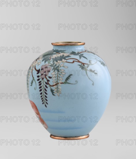 Vase by Gonda Hirosuke 1865–1937, cloisonné enamel, small spherical vase one of a pair on a low ring foot with a round ring spout, both set in silver-plated metal. Decorated with a realistic, colorful motif of red veil fish beneath hanging wisteria leaves and flowers on a light blue background. Bottom bears the enameller's mark: a flaming pearl with the katakana character ko Gonda Hirosuke of Nagoya. Circa 1890–1910 Meiji 23–43, Nagoya, Japan. Vessel; height 9.0 cm, diameter 8.2 cm., A smooth rounded vase with a pale blue background featuring a hanging floral design in shades of white, purple, dark green, and brown, with a few elongated leaf clusters and curved stems; the vase has metallic gold or bronze rims at the top and base and a small section of reddish-orange visible near the lower side.
