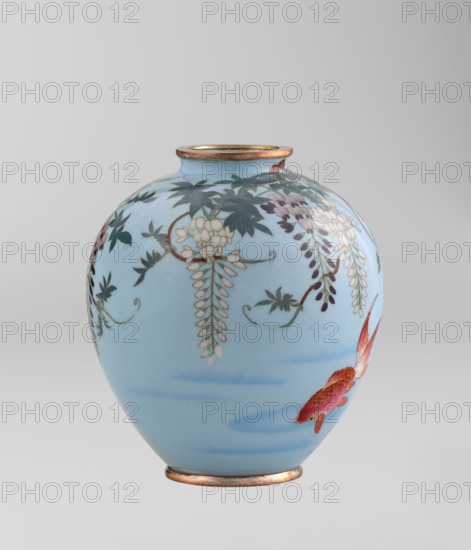 Vase by Gonda Hirosuke 1865–1937, cloisonné enamel, circa 1890–1910 Meiji 23–43, Nagoya, Japan. Small spherical vase, one of a pair, on a low ring foot and a round ring spout, both set in silver-plated metal. Decorated with realistically depicted colorful red veil fish beneath hanging wisteria leaves and flowers on a light blue background. Bottom bears a maker’s mark in the form of a flaming pearl with the katakana character ko — the brand of enameller Gonda Hirosuke. Height 9.0 cm; diameter 8.2 cm., A rounded ceramic vase with a pale blue background showing decorative hanging flowers and leaves in shades of dark green, pale cream, and muted purple, with a painted fish in shades of red and orange near the lower side, a narrow mouth and base rim with a metallic bronze tone, and soft blue brush strokes suggesting water.