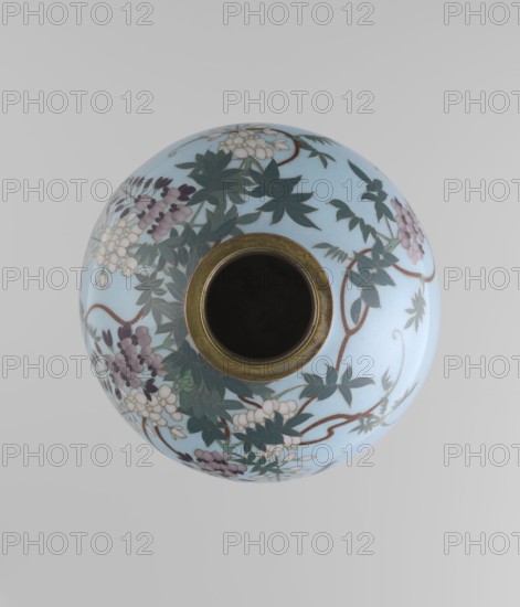 Vase, Gonda Hirosuke 1865–1937 author, Japanese, Meiji 1868–1912. Small spherical cloisonné enamel vase, one of a pair, on a low ring foot and a round ring spout, both set in silver-plated metal. Decorated with a realistic, colorful motif of red veil fish beneath hanging wisteria leaves and flowers on a light blue background. The bottom bears a maker’s mark in the form of a flaming pearl with the katakana character ? ko, the mark of enameller Gonda Hirosuke of Nagoya. Circa 1890–1910. Height 9.0 cm; diameter 8.2 cm., A round ceramic vessel photographed from above with a light blue surface decorated with floral and leafy patterns in dark green, muted purple, pale pink, brown, white, and beige, featuring a circular dark interior rim with a metallic gold-colored band around its opening; the background is a soft pale gray.