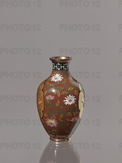Vase, phoenixes, lotuses, dragons, hoo phoenix, birds; cloisonné enamel vessel; Japan, Kyoto; Meiji period, ca. 1900–1910; height 12.3 cm, diameter 7.2 cm., A decorative vase with a rounded body and narrow neck sits against a plain gray background; the vase has a reddish-brown base color with swirling green vine patterns and floral motifs in white, pink, and yellow, a black band with white flower-like shapes around the neck, a metallic gold rim and base, and a glossy surface that reflects light.
