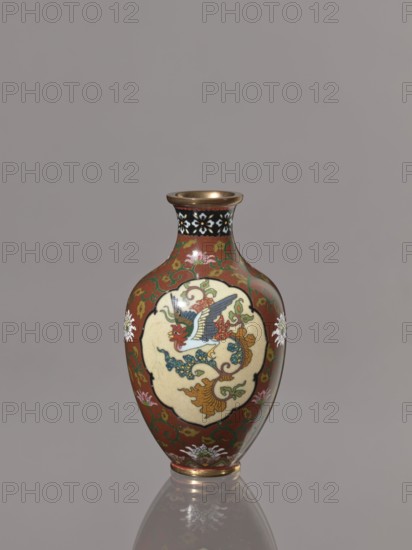 Vase, repossession; phoenixes hoo, lotuses, dragons, birds; cloisonné enamel; Japan, Kyoto; Meiji period, ca. 1900–1910; height 12.3 cm, diameter 7.2 cm., A small vase with a rounded body and narrow neck sits against a plain gray background; the vase has a reddish-brown base color with decorative green scrolling patterns and floral motifs in white and pink, a black band with white flowerlike shapes around the neck, and gold-colored rim and foot; an off-white cartouche on the front contains a multicolored bird motif with blue, red, green, and yellow details, and the vase surface shows glossy reflections.