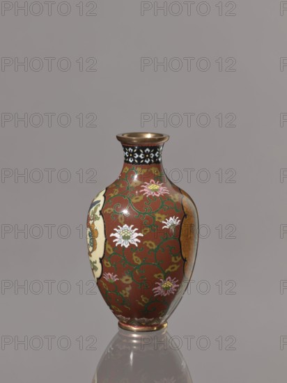 Vase, phoenixes iconography, Japanese art, lotuses, dragons iconography, Japanese culture, Meiji 1868–1912, hoo phoenix, birds, cloisonné enamel, ca. 1900–1910 Meiji Period, Japan, Kyoto, vessel, height 12.3 cm, diameter 7.2 cm, A small vase with a rounded body and narrow neck sits against a plain gray background, showing a glossy surface with a dominant reddish-brown color. The vase is decorated with swirling green vine patterns and several floral motifs in white and pale pink with yellow centers, and there are areas of cream and muted gold on its sides. The neck has a band with a black background and white floral shapes, and the rim and base have metallic gold tones. The vase casts a subtle reflection on the surface beneath it.