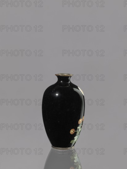 Vase, chrysanthemums, Japanese, flowers iconography, Meiji 1868–1912, cloisonné enamel, ovoid elongated vase, 19th/20th century Meiji period, Japan; vessel; height 9.0 cm, diameter 5.3 cm., A glossy black vase with a rounded body and narrow neck sits against a gray background, showing a delicate floral decoration on one side with pale green leaves and small orange flowers, and a slightly reflective base that mirrors the lower part of the vase; visible colors include black, gray, pale green, orange, and a hint of metallic at the rim.