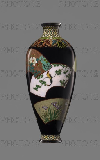 Vase by Namikawa Yasuyuki 1845–1927, cloisonné enamel, ca. 1890–1905 Meiji period. A small, slender vase tapering toward the bottom and terminating in a ring-shaped silver foot. The short neck is slightly parted at the spout and enclosed by a silver ring. An ornamental shippo motif border with rosettes in rhomboid fields decorates the foot and neck. Petal decorations filled with stylized phoenix images flow down to the shoulders. The belly is covered with shiny black enamel and features six colorful fan-shaped reserves with various floral and bird motifs, executed in the yusen technique with silver wires. A silver plaque mounted in the mirror of the bottom is engraved “Kyoto Namikawa.” Origin: Kyoto, Japan. Height 18.0 cm; diameter 7.8 cm., A tall, elongated vase with a glossy black background decorated with several fan-shaped panels showing floral and bird motifs; the neck and base have geometric patterned bands in shades of yellow, green, blue, and black, while the body panels featur...